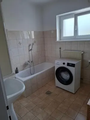 a bathroom with a washing machine next to a bath tub at Apartma LONČAR in Horjul
