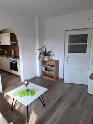 a living room with a table and a kitchen at Apartma LONČAR in Horjul