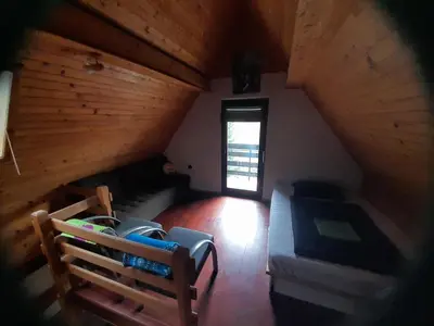 an attic room with a couch and a bed and a window at Owl's Nest Bovec in Bovec