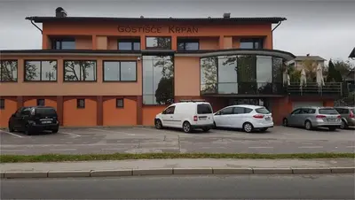 a building with cars parked in a parking lot at Gostišče Krpan in Grosuplje