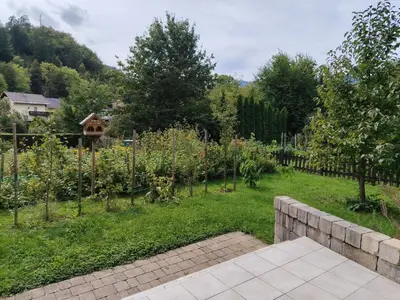 a garden with a stone wall and trees and a fence at Apartment Green Oasis in Bled