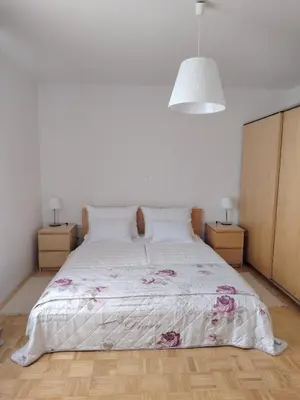 a bedroom with a white bed with pink flowers on it at Apartment Green Oasis in Bled