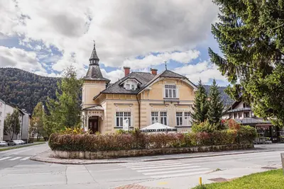 a large yellow building with a tower on a street at Guest House Veronika in Kočevje