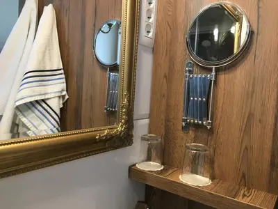 a mirror on a wall next to a wooden shelf at Guest House Veronika in Kočevje