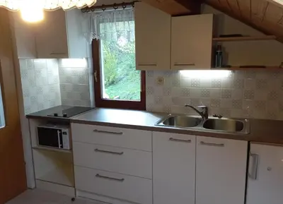 a kitchen with white cabinets and a sink and a window at Apartment Jakelj in Kranjska Gora