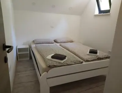 a small bedroom with two beds and a window at Apartma Jezero in Grahovo