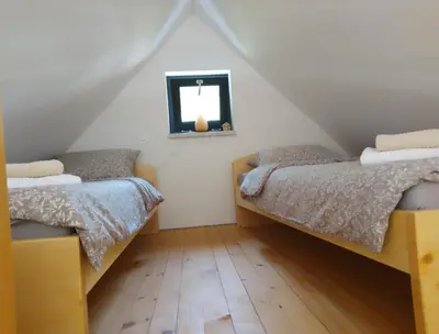 two beds in a attic bedroom with a window at Apartma Jezero in Grahovo