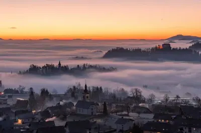 a view of a town in the fog at sunset at Marta's House in Bled