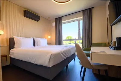 a hotel room with a bed and a desk and a window at Hotel Adore in Ljubljana