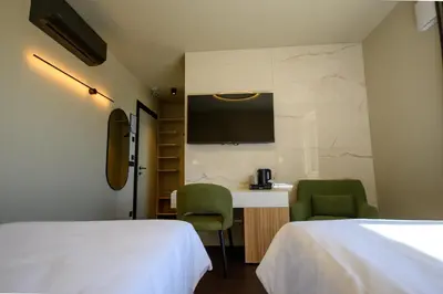 a hotel room with two beds and a desk at Hotel Adore in Ljubljana