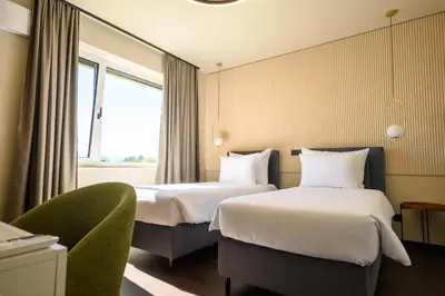 a hotel room with two beds and a chair at Hotel Adore in Ljubljana