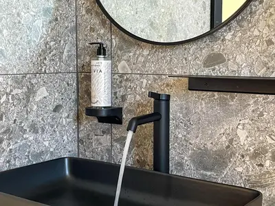 a sink with a soap dispenser next to a mirror at Hotel Adore in Ljubljana
