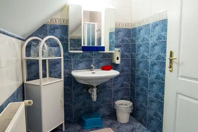 a blue tiled bathroom with a sink and a mirror at Vila Šiftar in Moravske Toplice