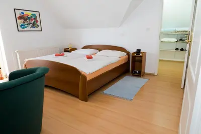 a bedroom with a bed with white sheets and a wooden floor at Vila Šiftar in Moravske Toplice