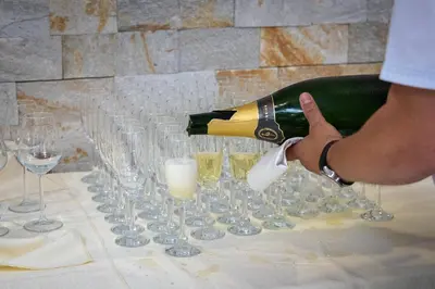 a person pouring a bottle of wine in wine glasses at Guesthouse Siva Čaplja in Videm pri Ptuju