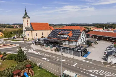 an aerial view of a town with a church with solar panels at Guesthouse Siva Čaplja in Videm pri Ptuju