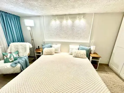 a bedroom with a large bed and a chair at New comfortable and cute one-room apartment of 33 m2 in Ljubljana