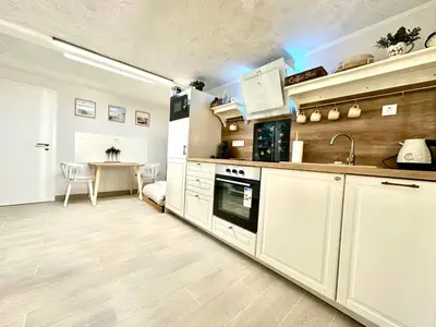 a kitchen with white cabinets and a table in the background at New comfortable and cute one-room apartment of 33 m2 in Ljubljana