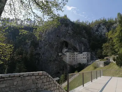 a building on a cliff with a mountain at SiJu loft bed in Postojna