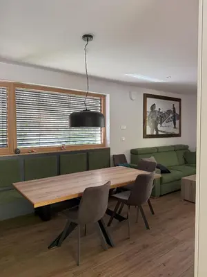 a living room with a wooden table and a green couch at Charming house in Gozd Martuljek in Gozd Martuljek