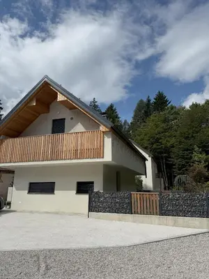 a white house with a wooden fence in front of it at Charming house in Gozd Martuljek in Gozd Martuljek