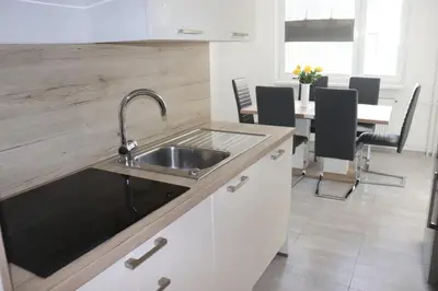 a kitchen with a sink and a table with chairs at Apartment Valis in Velenje