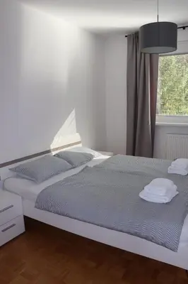 a white bedroom with a bed and a window at Apartment Valis in Velenje