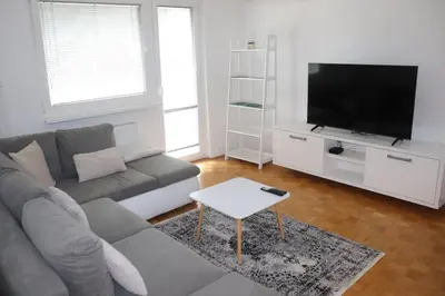 a living room with a gray couch and a flat screen tv at Apartment Valis in Velenje