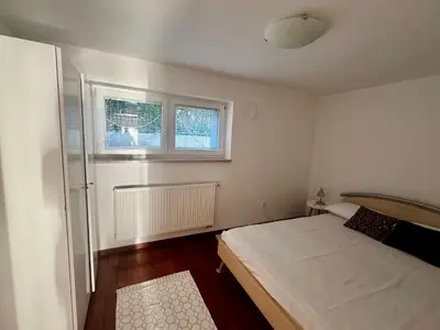 a small bedroom with a bed and two windows at Ljubljana Garden Apartment - Free Parking in Ljubljana