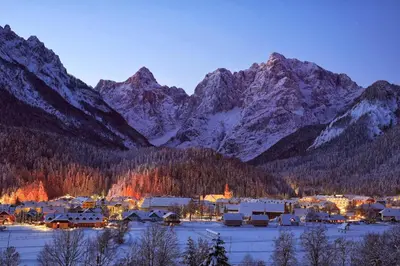 a small town in front of a snowy mountain range at Apartments Demec in Kranjska Gora