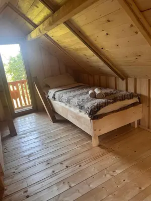 a bed in the attic of a wooden cabin at Tree house - Ethno holistic village Apače in Apače