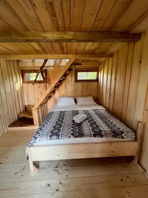 a bed in the middle of a wooden cabin at Tree house - Ethno holistic village Apače in Apače