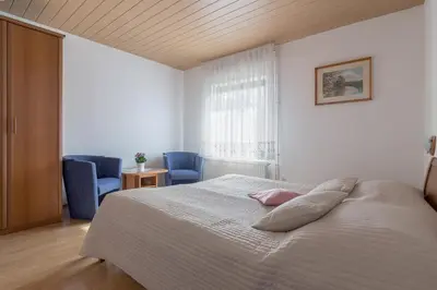 a bedroom with a bed and two blue chairs at Apartments Fine Stay Bled in Bled