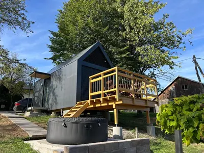 a small black house with a wooden deck at La - Mai Glamping in Žetale