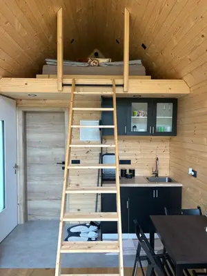 a loft bed in the kitchen of a tiny house at La - Mai Glamping in Žetale