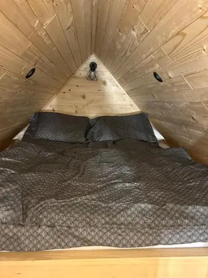 a bed in a small room with a wooden ceiling at La - Mai Glamping in Žetale
