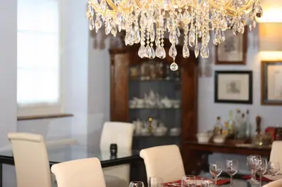 a dining room with a chandelier and a table with white chairs at The Blue House in Tolmin