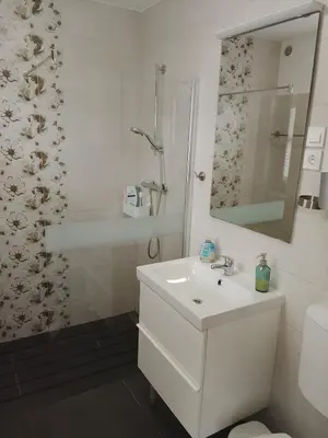 a white bathroom with a sink and a mirror at Emma's Holiday Home in Brežice