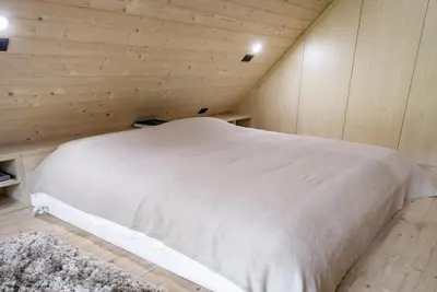a bedroom with a white bed in a wooden wall at Chalet Aurora