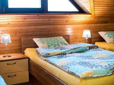 a bedroom with two beds with wooden walls and two lamps at Relaxing Retreat with Hot Tub in Sevnica - Three Bedroom Apartment in Sevnica