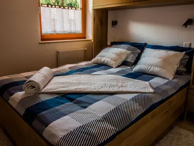 a bed with a blue and white blanket and pillows at Riverside Pines Luce Apartments with Balcony - Two Bedroom Apartment with Balcony in Luče