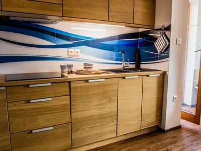 a kitchen with wooden cabinets and a blue and white wall at Riverside Pines Luce Apartments with Balcony - Two Bedroom Apartment with Balcony in Luče