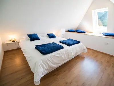 a bedroom with a white bed with blue pillows on it at Mountain View Haven Apartments - One Bedroom Apartment with Balcony in Bovec