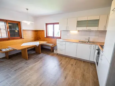 a kitchen with white cabinets and a wooden table at Serene Hollow Holiday Home with Mountain View - Two Bedroom Holiday Home with Mountain View in Cerklje ob Krki