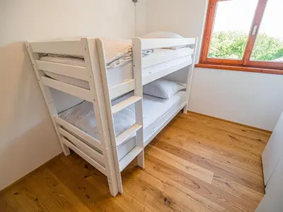 a bunk bed in a room with a window at Serene Hollow Holiday Home with Mountain View - Two Bedroom Holiday Home with Mountain View in Cerklje ob Krki