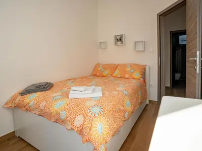 a small bedroom with a bed with an orange bedspread at Three Bedroom Holiday Home with Terrace and Sauna in Tolmin