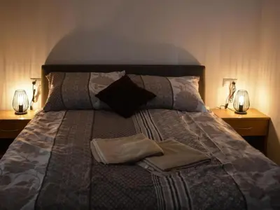 a bed with pillows and two lamps on two tables at One Bedroom Apartment in Brežice