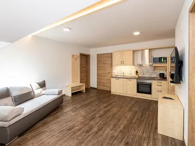 a living room with a couch and a kitchen at The Woodland Nook Apartments Bohinj - One Bedroom Apartment in Bohinj
