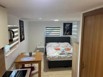 a small bedroom with a bed and a table at Meadow Tranquil Apartments with Evergreen Garden - Studio Apartment in Žirovnica