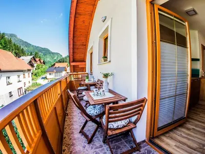 a balcony with a wooden table and chairs on it at Riverside Pines Luce Apartments with Balcony - One Bedroom Apartment with Balcony in Luče